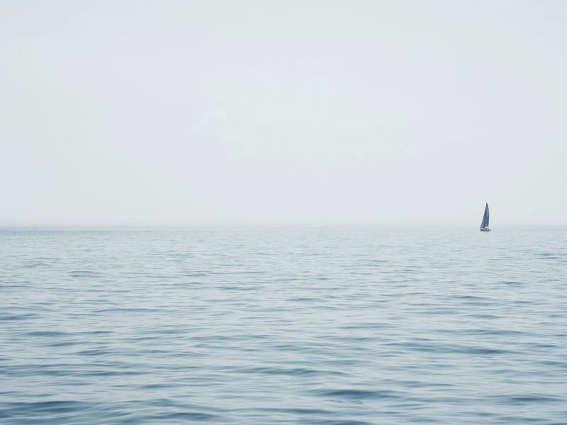 A lone sailing yacht on a still sea